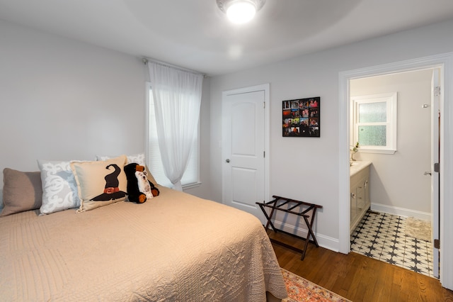 bedroom with ensuite bathroom and dark hardwood / wood-style flooring