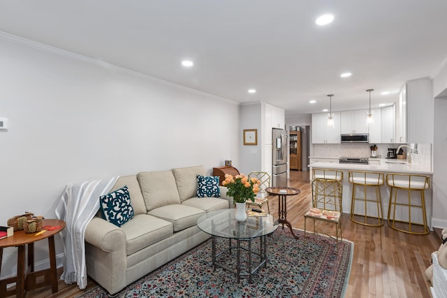 living room with hardwood / wood-style flooring, ornamental molding, and sink