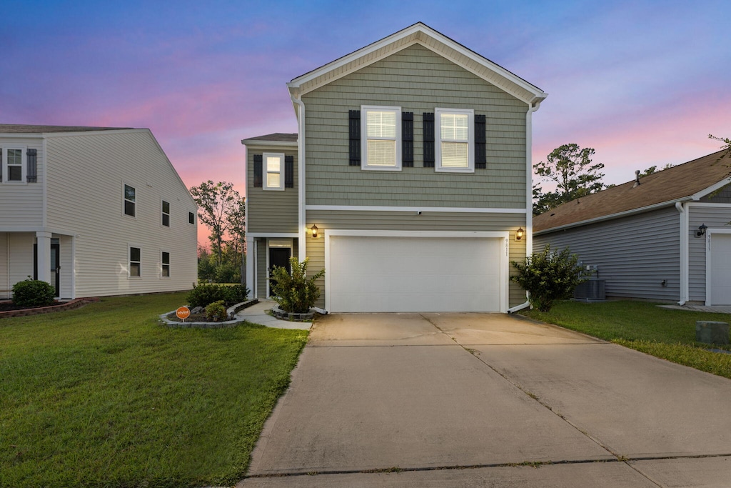 view of front of property with central air condition unit, a garage, and a lawn