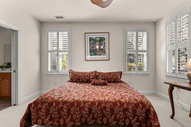 carpeted bedroom featuring multiple windows and baseboards