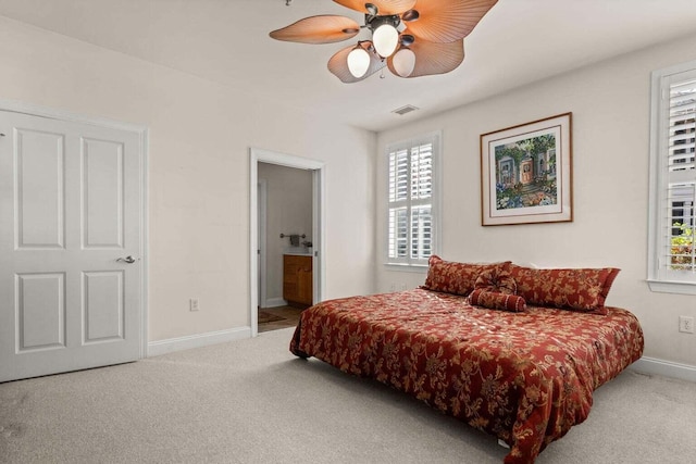 carpeted bedroom with baseboards, connected bathroom, and a ceiling fan