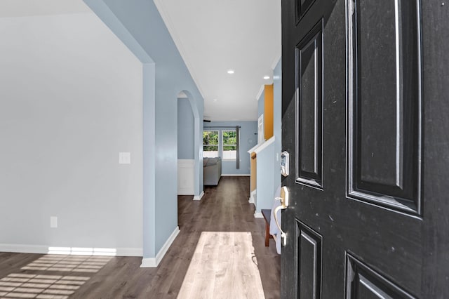 foyer entrance with ornamental molding and dark wood-type flooring