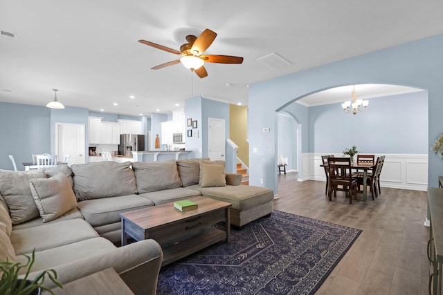 living room featuring ornamental molding, ceiling fan with notable chandelier, and hardwood / wood-style flooring