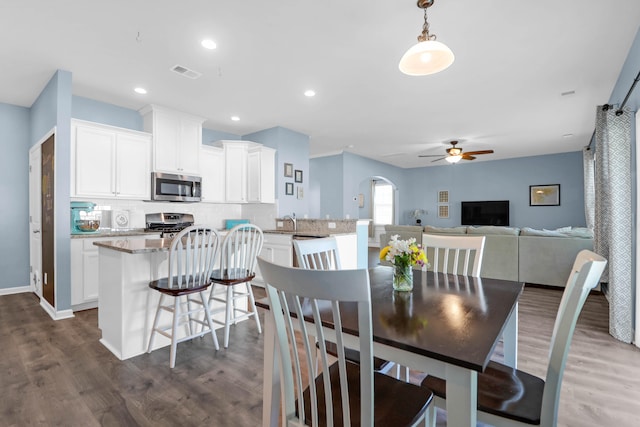 dining area with ceiling fan, sink, and dark hardwood / wood-style floors