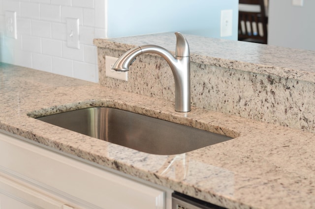 room details featuring light stone countertops, tasteful backsplash, and sink