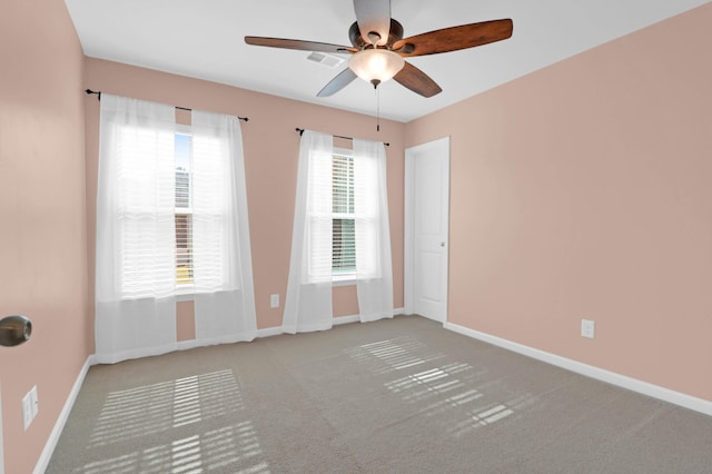 carpeted spare room featuring ceiling fan and a wealth of natural light