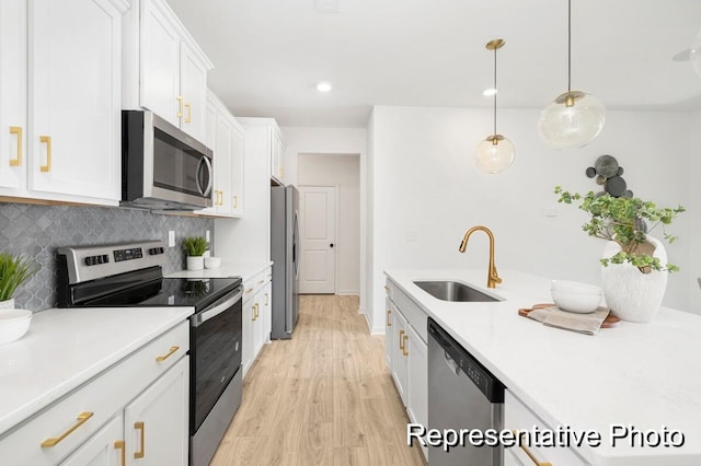 kitchen featuring pendant lighting, tasteful backsplash, sink, white cabinets, and stainless steel appliances