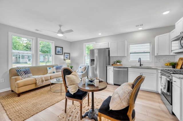 kitchen with white cabinets, appliances with stainless steel finishes, plenty of natural light, and light stone countertops