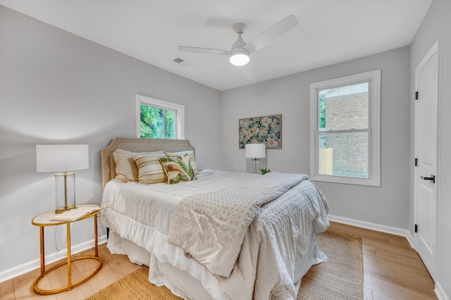 bedroom with ceiling fan, hardwood / wood-style floors, and multiple windows