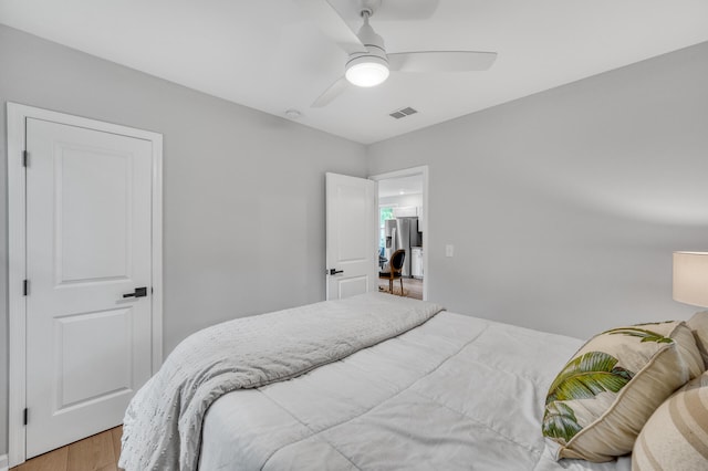 bedroom with stainless steel fridge, ceiling fan, and light hardwood / wood-style flooring