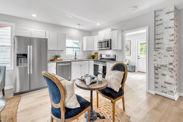 kitchen with light wood-type flooring, appliances with stainless steel finishes, sink, and white cabinets