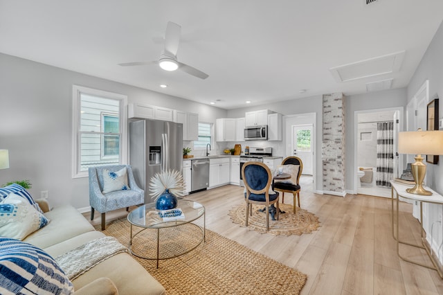 living room with light wood-type flooring, a healthy amount of sunlight, sink, and ceiling fan