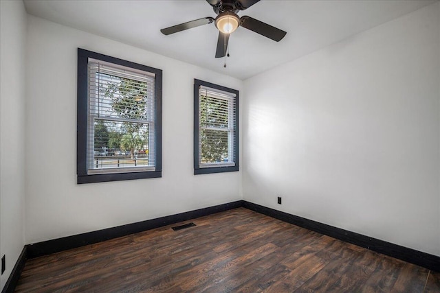 spare room featuring a ceiling fan, baseboards, visible vents, and dark wood-style flooring