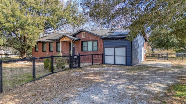 view of front facade with fence private yard, solar panels, brick siding, driveway, and a gate