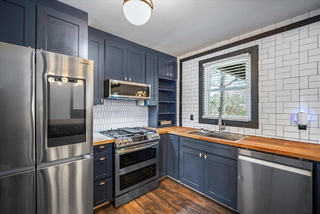 kitchen featuring appliances with stainless steel finishes, wooden counters, decorative backsplash, and a sink