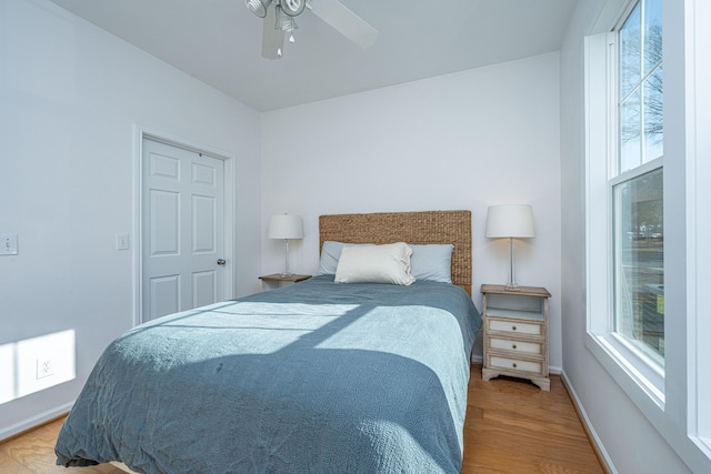 bedroom with ceiling fan, multiple windows, and light hardwood / wood-style flooring