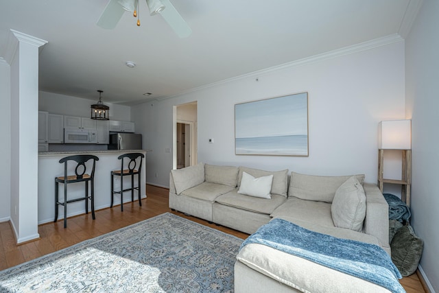 living room featuring ceiling fan, wood-type flooring, and crown molding