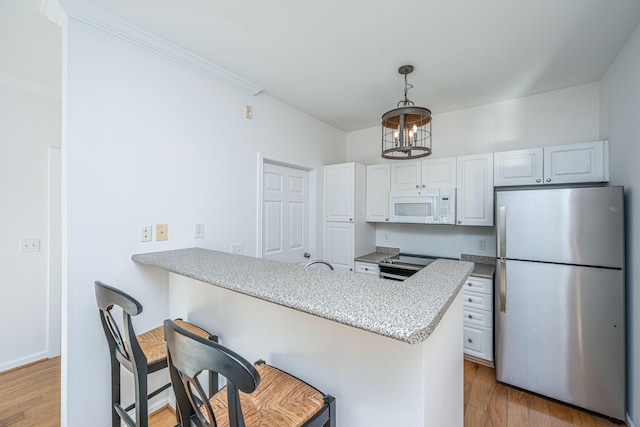 kitchen featuring white cabinets, appliances with stainless steel finishes, kitchen peninsula, and a breakfast bar