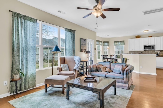 living room with light hardwood / wood-style floors and ceiling fan