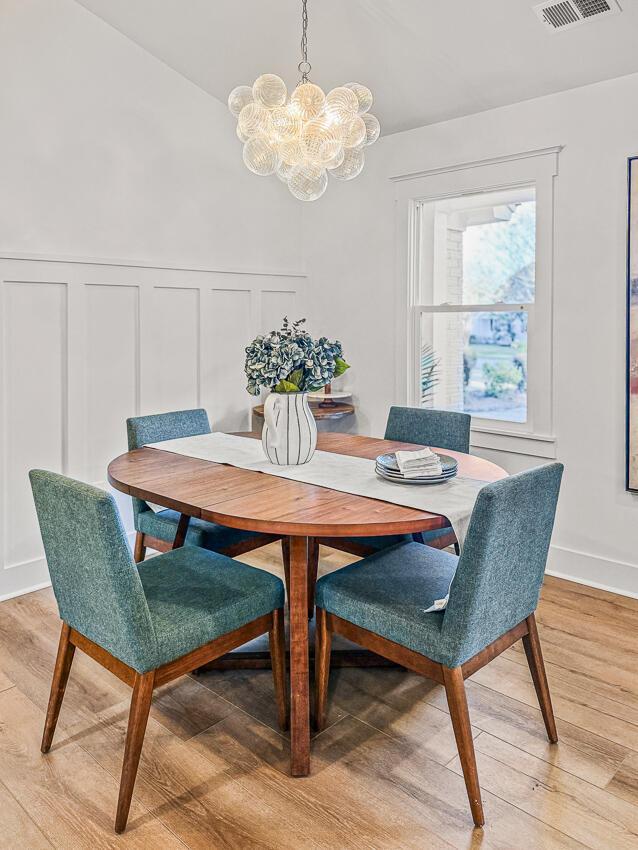 dining space featuring an inviting chandelier, vaulted ceiling, and light hardwood / wood-style floors