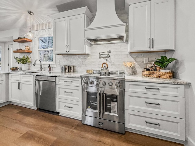 kitchen with appliances with stainless steel finishes, white cabinetry, sink, backsplash, and custom exhaust hood