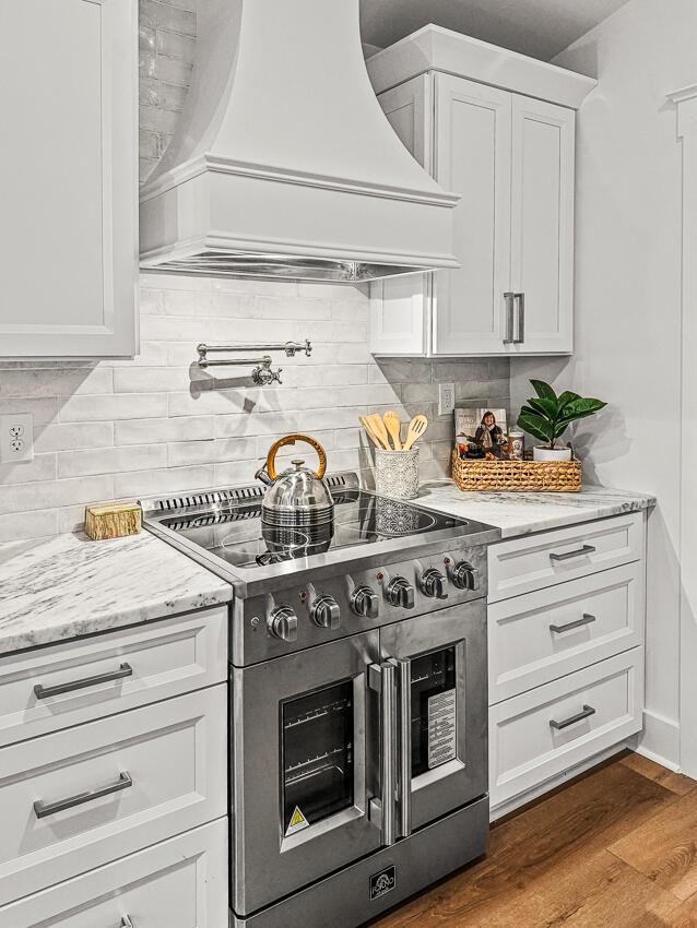 kitchen featuring white cabinetry, stainless steel stove, custom range hood, and hardwood / wood-style flooring