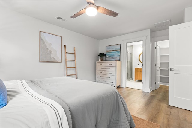 bedroom featuring connected bathroom, hardwood / wood-style floors, a walk in closet, and ceiling fan