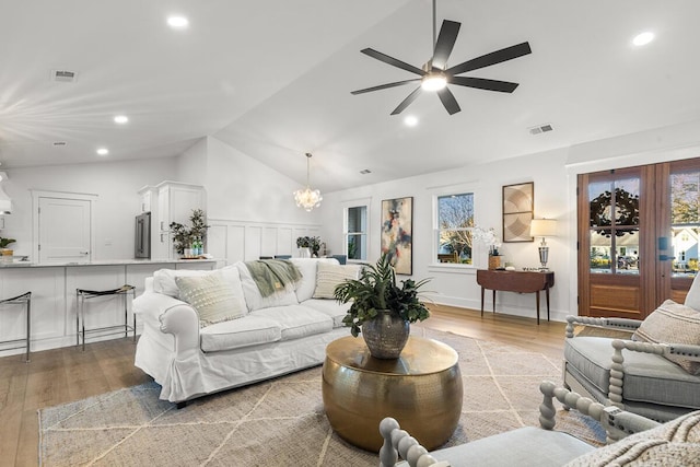 living room with lofted ceiling, ceiling fan with notable chandelier, light hardwood / wood-style flooring, and plenty of natural light