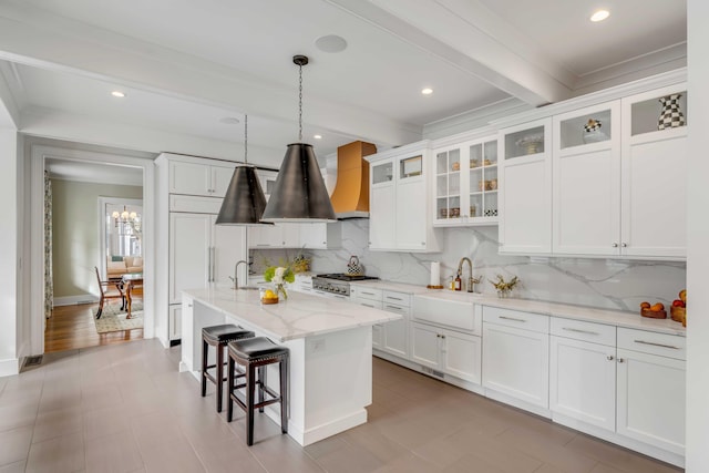 kitchen with beam ceiling, white cabinets, and a sink