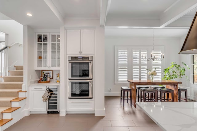 kitchen featuring wine cooler, stainless steel double oven, glass insert cabinets, and white cabinets