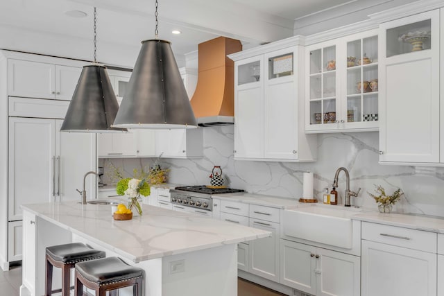 kitchen with stove, a sink, white cabinetry, and custom range hood