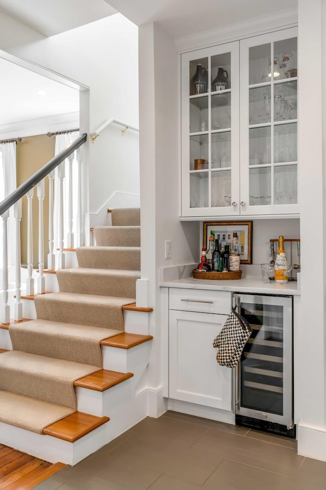 bar featuring beverage cooler, a bar, and stairway