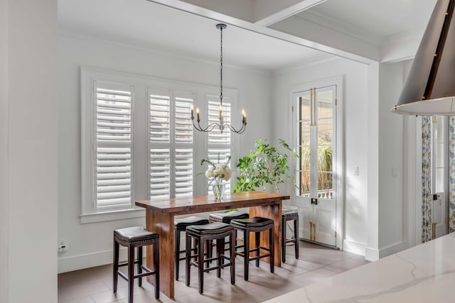 dining space with an inviting chandelier, baseboards, light tile patterned floors, and ornamental molding