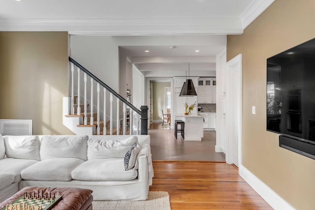 entrance foyer featuring visible vents, stairway, light wood-style flooring, ornamental molding, and baseboards