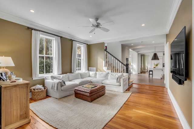 living area with stairway, crown molding, light wood-style flooring, and baseboards