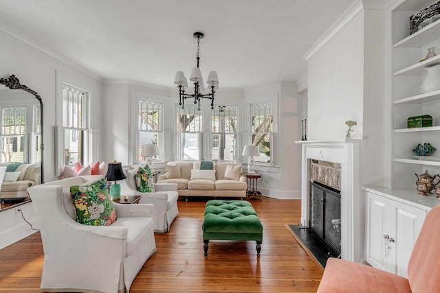 living room featuring hardwood / wood-style flooring, a fireplace with flush hearth, ornamental molding, and an inviting chandelier