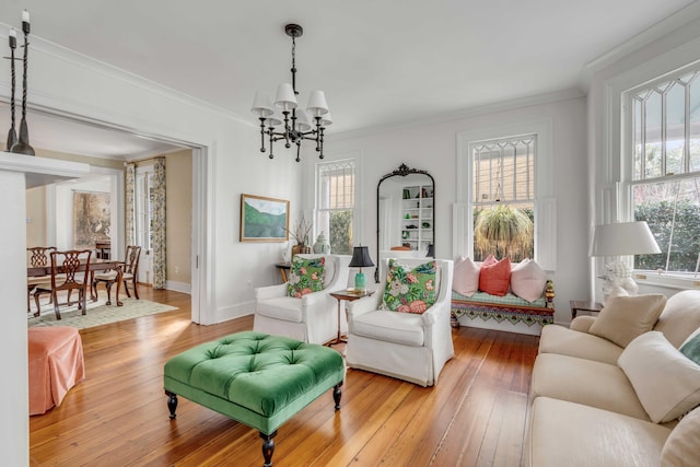 living area with ornamental molding, plenty of natural light, light wood-style floors, and an inviting chandelier