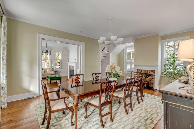 dining area featuring a fireplace, light wood-style flooring, and a notable chandelier