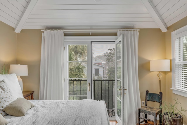 bedroom with access to exterior, multiple windows, and lofted ceiling with beams