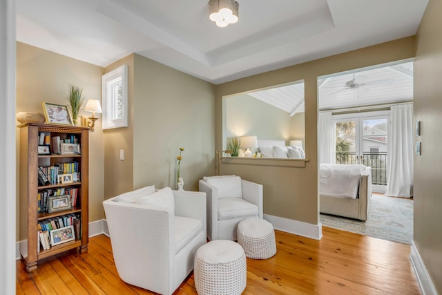 sitting room featuring light wood-style floors, baseboards, and a raised ceiling