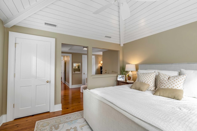 bedroom featuring visible vents, lofted ceiling with beams, baseboards, and wood finished floors