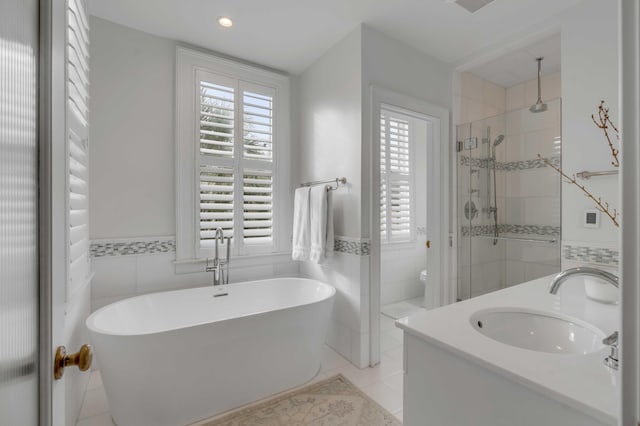 bathroom featuring a freestanding tub, toilet, a sink, tile walls, and a shower stall