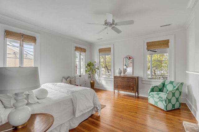 bedroom featuring light wood finished floors, baseboards, visible vents, a ceiling fan, and ornamental molding