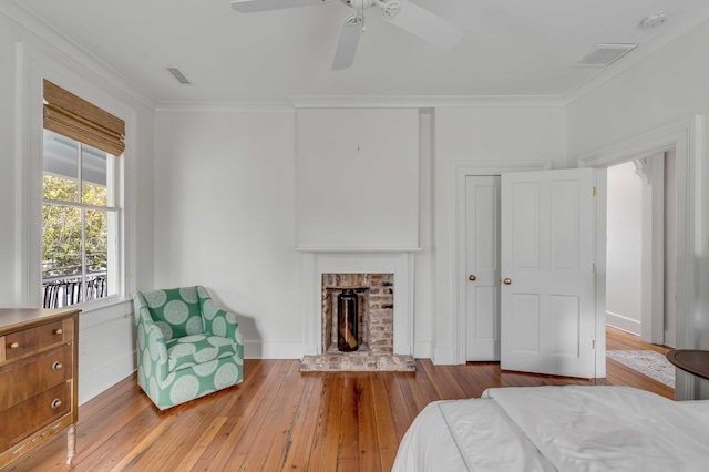 bedroom featuring crown molding, wood-type flooring, visible vents, and a fireplace