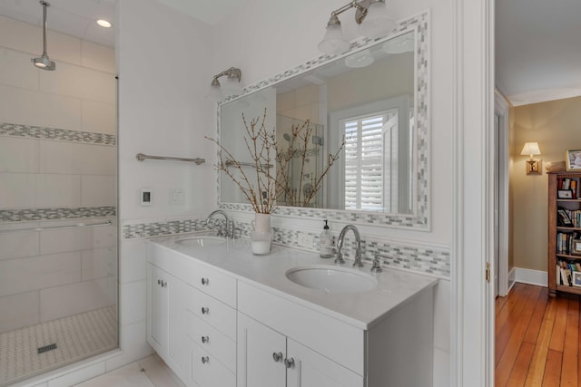 full bathroom featuring double vanity, wood finished floors, a sink, and a shower stall