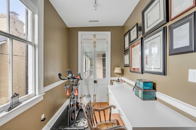 workout room with a wealth of natural light, light wood-style flooring, rail lighting, and visible vents