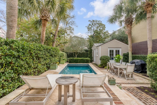 pool featuring a patio, area for grilling, fence, an exterior structure, and an outdoor structure