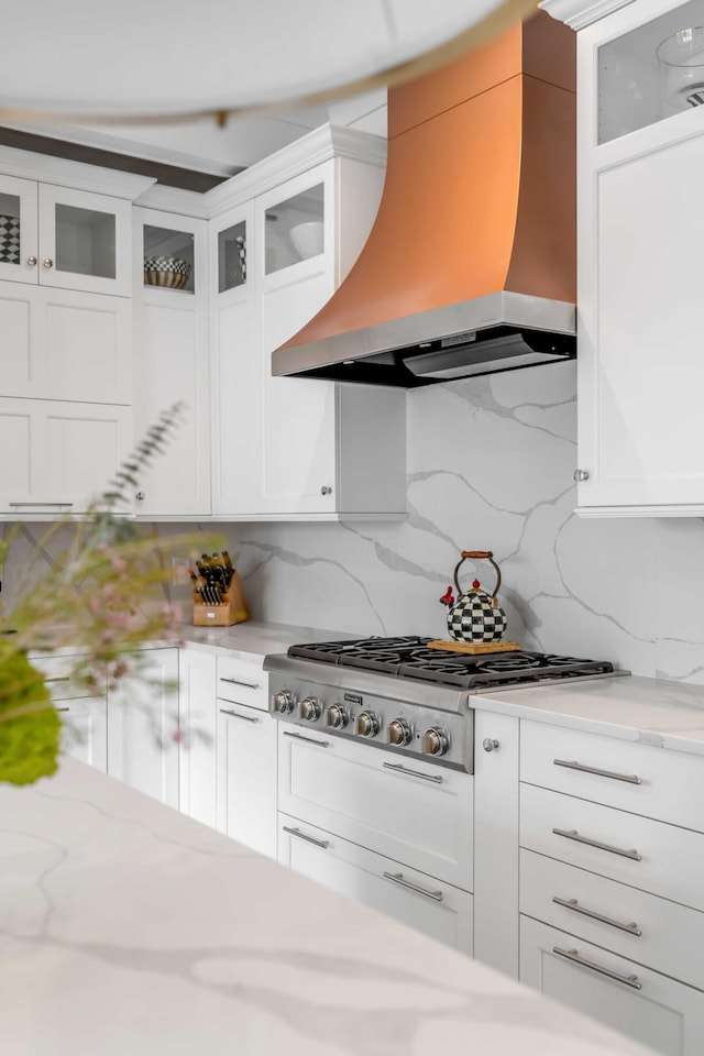 kitchen featuring light stone counters, premium range hood, white cabinetry, and stainless steel gas stovetop