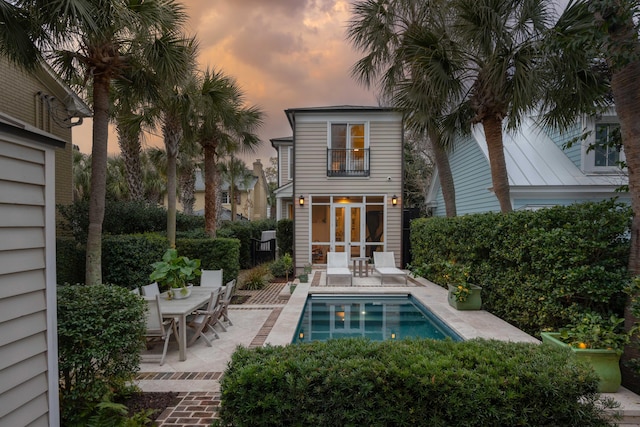 back of house featuring a patio, outdoor dining area, a balcony, and a fenced in pool