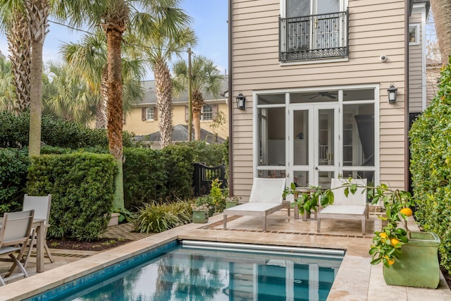 rear view of property featuring an outdoor pool, a patio, and a balcony